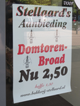 908355 Afbeelding van een reclamebiljet voor 'Domtoren Broad', geplakt op een winkelruit van Bakkerij Stellaard ...
